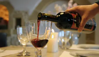 a person pouring red wine into a wine glass at Villa Meli-milon in Kolymvari