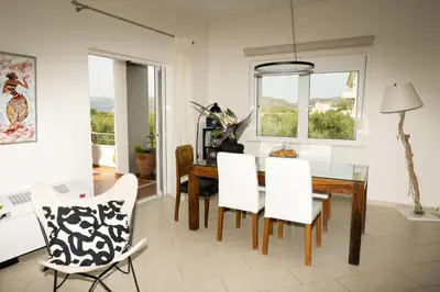 a dining room with a glass table and white chairs at Elia Seaside Villa, Amazing 2-Story Eco Pool House! in Kissamos