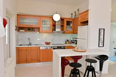 a kitchen with wooden cabinets and a kitchen island with bar stools at Elia Seaside Villa, Amazing 2-Story Eco Pool House! in Kissamos