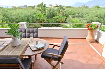 a patio with a table and chairs on a balcony at Elia Seaside Villa, Amazing 2-Story Eco Pool House! in Kissamos