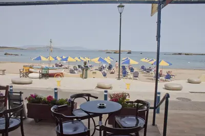 a beach with tables and chairs and people on the beach at Danaos Hotel in Chania Town