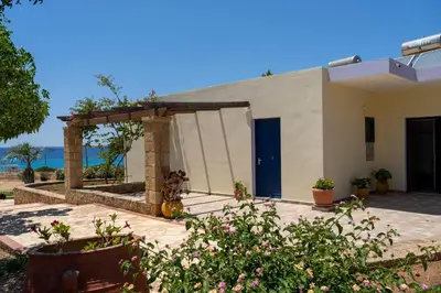 a white building with a blue door and some plants at Adam in Falasarna