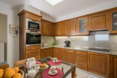 a kitchen with wooden cabinets and a glass table at Vaggelio House in Chania Town