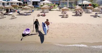 two people walking on the beach with their surfboards at Christina Beach Hotel in Chania Town