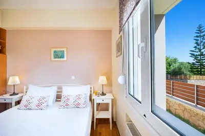 a bedroom with a bed and a large window at Vrahokipos Villa in Kounoupidhianá