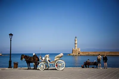 a horse drawn carriage on a pier with a lighthouse at La Casa Piccola in Chania Town