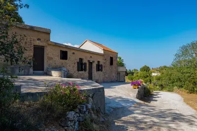 an external view of a stone house with flowers at Lithari in Kámboi