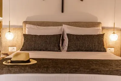 a hat sitting on top of a bed with pillows at Lithinon Luxury Suites with Free Parking in Chania Town