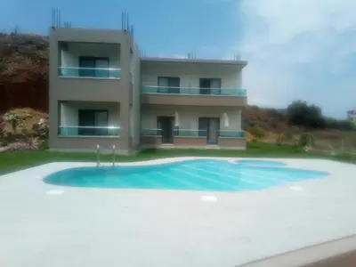 a house with a swimming pool in front of a building at Efrilias Studios & Apartments in Kissamos