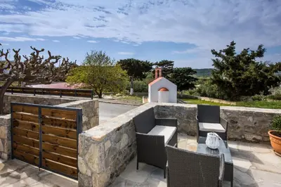 a patio with a stone wall and chairs and a table at Lardas Luxury Country House in Kissamos