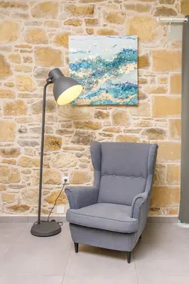 a lamp in a living room with a chair and a painting at Villa Agrithea in Kissamos