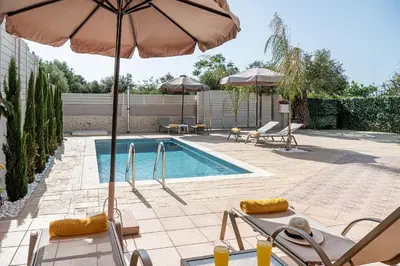 a pool with chairs and umbrellas and a swimming pool at Villa Fanouris in Chania Town