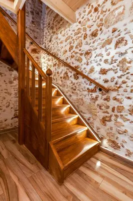 a wooden staircase in a room with a stone wall at Hamam Suites Portou in Chania Town
