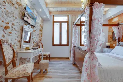 a bedroom with a four poster bed and a desk at Hamam Suites Portou in Chania Town