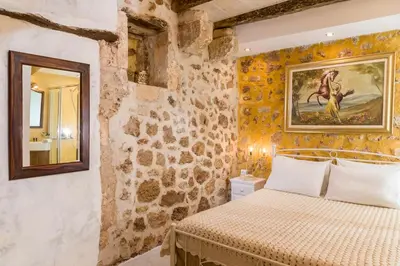 a bedroom with a bed and a painting on the wall at Hamam Suites Portou in Chania Town