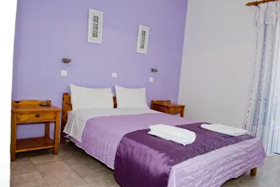 a purple bedroom with a bed with two towels on it at Blue Sky in Palaiochóra