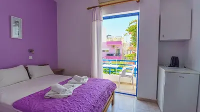 a bedroom with a bed with purple sheets and a window at Blue Sky in Palaiochóra