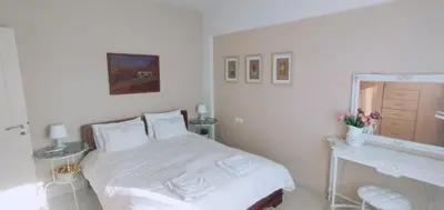 a white bedroom with a bed and a mirror at The Garden of Zephyrus - West in Kounoupidhianá