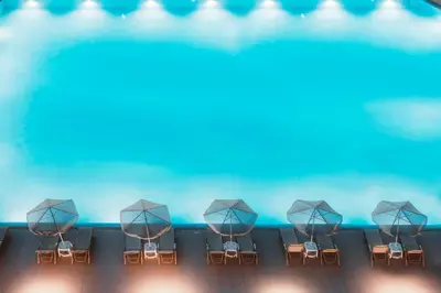 a row of chairs and umbrellas in front of a pool at Giannoulis – Santa Marina Beach Hotel in Agia Marina Nea Kydonias