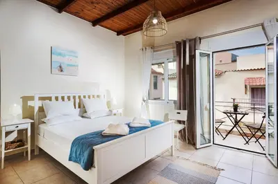 a white bedroom with a bed and a balcony at Kd's - Apartment in Chania Town