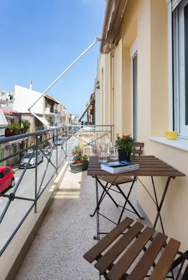 a balcony with a wooden table and bench on a building at Kd's - Apartment in Chania Town