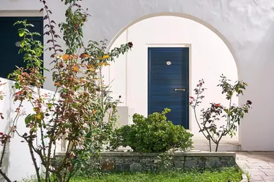 a blue door in a white house with plants at Eva Suites & Apartments in Agia Marina Nea Kydonias