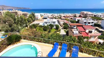 a view of the beach from a resort with blue chairs at Blue Villas in Agia Marina Nea Kydonias