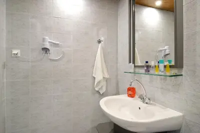 a white bathroom with a sink and a mirror at Mythos- Platanias- Hotel -Apts in Plataniás