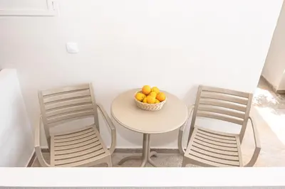 a table with two chairs and a bowl of oranges at Talos Hotel Apartments in Kato Daratso