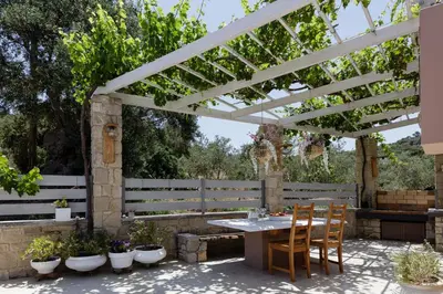 a patio with a table and chairs under a pergola at Villa Veni in Kolymvari