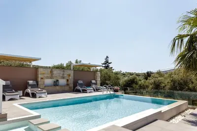 a swimming pool in a backyard with chairs and a house at Villa Veni in Kolymvari