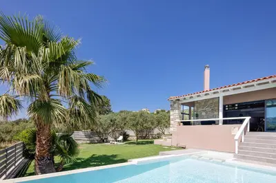 a villa with a palm tree and a swimming pool at Villa Veni in Kolymvari