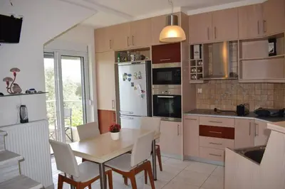 a kitchen with a table and a white refrigerator at ILIAS VILLA IN CHANIA in Perivólia