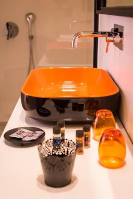 an orange sink on a bathroom counter with cosmetics at TheJoy City Suites in Chania Town