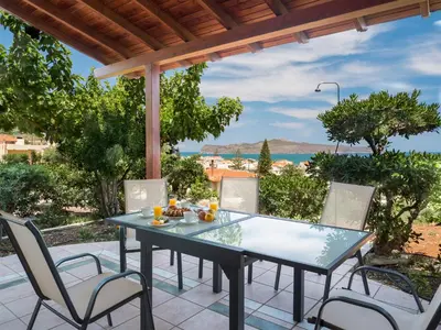 a table and chairs on a patio with a view of the ocean at Romantic Corner Maisonette houses in Stalos