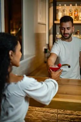 a woman sitting at a bar talking to a bartender at Theos Village Apartments in Kato Daratso