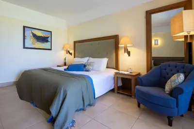 a hotel room with a bed and a blue chair at Giannoulis – Cavo Spada Luxury Sports & Leisure Resort & Spa in Kolymvari