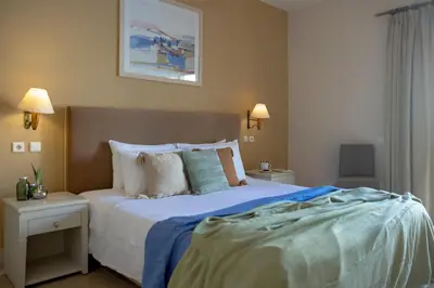 a bedroom with a large bed with blue sheets and pillows at Giannoulis - Grand Bay Beach Resort (Exclusive Adults Only) in Kolymvari