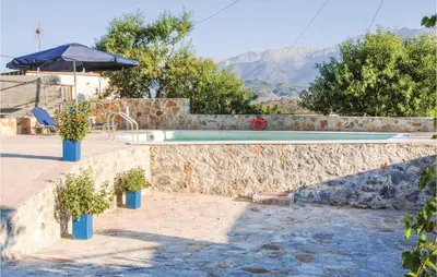 a swimming pool with potted plants in front of a house at Amazing Home In Malaxa, Chania in Maláxa