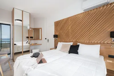 a bedroom with a large white bed with a wooden headboard at Elia Penthouse in Chania Town