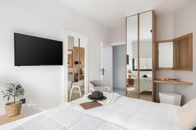 a white bedroom with a large bed with a flat screen tv at Elia Penthouse in Chania Town