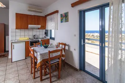 a kitchen with a table with chairs and a view of the ocean at Roula Apartments in Palaiochóra