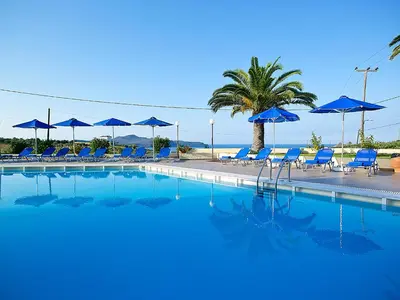 a swimming pool with blue chairs and umbrellas at Eleftheria Hotel in Agia Marina Nea Kydonias