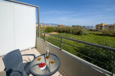 a table and a chair on a balcony with a view at Bella Pais in Maleme