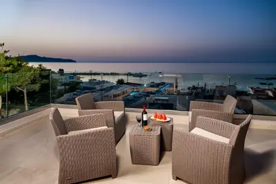 a patio with chairs and a table with a view of the ocean at Eland Dream Villas in Kalamaki Chanion