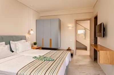 a bedroom with a large white bed and a television at Eland Dream Villas in Kalamaki Chanion