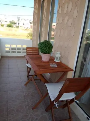 a wooden table and bench on a balcony with a potted plant at Beachway home in Kato Daratso
