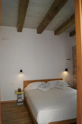 a bedroom with a bed with white sheets and wooden ceilings at Casa al Bocca del Porto in Chania Town