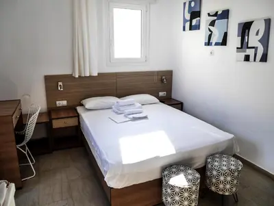 a bedroom with a bed and a desk and a window at Georgia in Palaiochóra