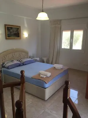 a bedroom with a bed with blue sheets and a window at The Endless Blue Maisonette in Palaiochóra